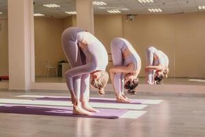 bem olhando meio envelhecido desportivo mulher, ginástica instrutor dentro Rosa roupa de esporte fazendo alongamento e pilates em ioga esteira dentro a estúdio com espelho. fêmea ginástica ioga. saudável estilo de vida e harmonia. foto