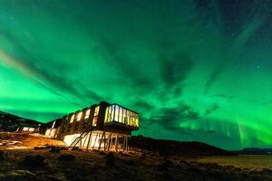 aurora boreal, norte luzes brilhando sobre luxo hotel em vulcânico região selvagem dentro inverno às Islândia foto