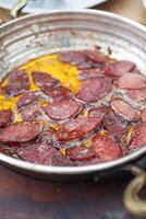 cozinhando uma prato do café da manhã linguiça dentro uma panela em uma de madeira mesa foto