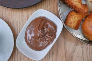 uma tigela do chocolate creme e pão em uma mesa foto