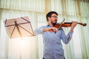 homem jogando violino às lar. ele é praticando para viver desempenho. foto