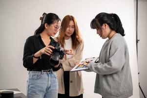 uma profissional ásia fêmea fotógrafo falando com assistentes, preparando antes uma tiroteio. foto