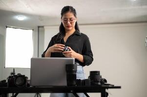 uma fêmea fotógrafo é preparando dela câmeras lente para uma sessão de fotos, trabalhando dentro uma estúdio. foto