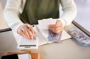 uma fêmea pequeno o negócio proprietário usando uma calculadora, calculando contas, planejamento dela fazer compras despesas. foto
