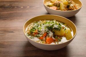 frango sopa com legumes dentro uma profundo tigela em uma de madeira mesa. foto