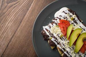 enfrijoladas servidas em prato de barro. comida típica mexicana. tacos de feijão com creme e queijo. foto