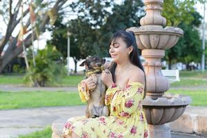 mulher abraçando dela animal dentro uma público jardim às pôr do sol. cachorro amante. foto