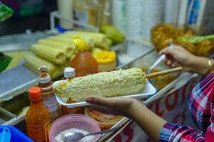 mexicano mulher preparando uma fervido milho, típica mexicano rua Comida. Comida parar. elote. foto