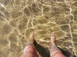 com seu pés dentro a mar água foto