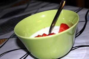 uma tigela do iogurte com morangos pronto para estar servido foto