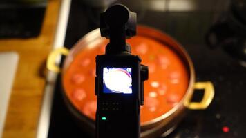 uma digital Câmera é filmando caseiro almôndegas fervendo dentro tomate molho foto