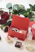 sortido chocolates transbordante dentro uma vibrante vermelho caixa foto