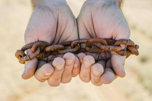 foto dois masculino mãos segurando uma oxidado metal cadeia