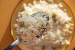 fechar-se do cozinhou branco arroz em uma colher foto