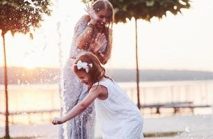 continua chegando. em um dia quente e ensolarado, a mãe e a filha decidem usar uma fonte para se refrescar e se divertir com ela foto