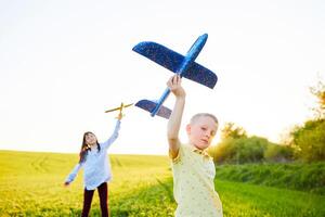 alegre e feliz crianças jogar dentro a campo e Imagine si mesmos para estar pilotos em uma ensolarado verão dia. crianças sonhos do vôo e aviação. foto