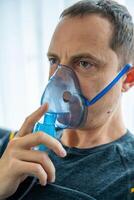 pouco saudável homem vestindo nebulizador mascarar dentro lar. saúde, médico equipamento e pessoas conceito. Alto qualidade foto