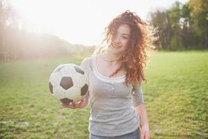 garota sexy jovem ruiva em jogador casual no estádio de futebol ao pôr do sol foto