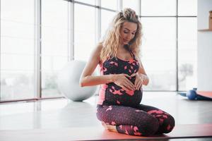 conceito de gravidez de ioga e fitness. retrato de um jovem modelo de uma mulher grávida em desenvolvimento dentro de casa.