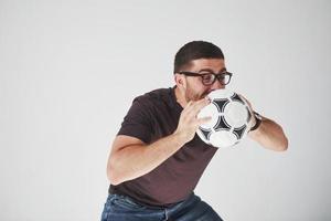 fã de futebol animado com uma bola de futebol isolada no fundo branco. ele pula está feliz e executa vários truques para torcer por seu time favorito foto