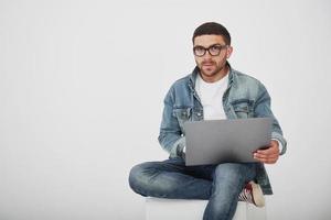 jovem bonito com laptop e verificar seu calendário em fundo branco foto