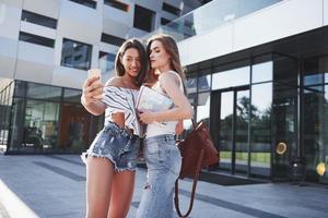 duas linda feliz jovem estudante com mochila perto do campus da universidade e fazer selfie foto. conceito de educação e lazer