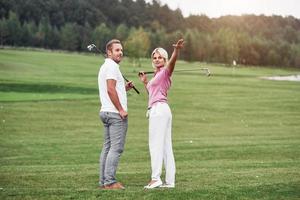 levantando a mão para mostrar o próximo destino. dois jogadores de golfe com tacos em pé no gramado foto