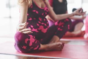 foto focada de duas mulheres grávidas sentadas em posição de ioga fazendo exercícios