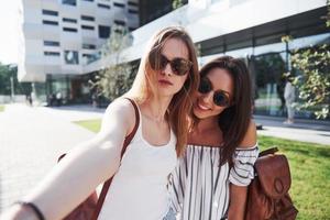 duas linda feliz jovem estudante com mochila perto do campus da universidade e fazer selfie foto. conceito de educação e lazer