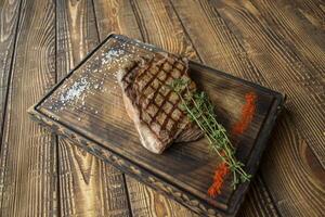 grelhado carne com molho e alecrim em uma de madeira mesa. foto