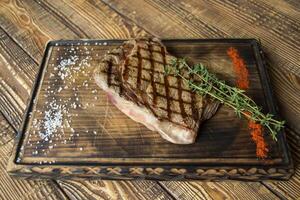 grelhado carne com molho e alecrim em uma de madeira mesa. foto