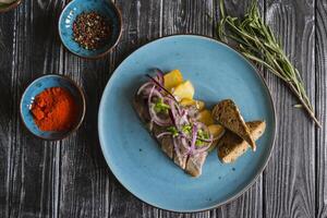 frito batatas e arenque peixe com cebola em uma de madeira mesa. foto