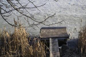 velho de madeira ponte dentro a congeladas lago. foto