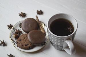 uma copo do café com chocolate biscoitos, em uma branco de madeira mesa. foto
