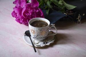 uma copo do café, peônias e fêmea bolsa. foto