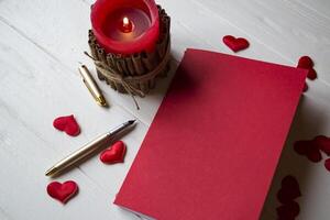 vermelho caderno, vela e amor corações em uma escrivaninha. foto