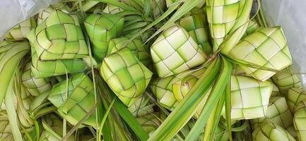 ketupat ou arroz bolinho de massa. uma tradicional arroz invólucro fez a partir de jovem coco folhas para cozinhando arroz vendido dentro tradicional mercado preparação para a eid al-fitr feriado para muçulmano foto