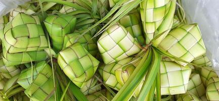 ketupat ou arroz bolinho de massa. uma tradicional arroz invólucro fez a partir de jovem coco folhas para cozinhando arroz vendido dentro tradicional mercado preparação para a eid al-fitr feriado para muçulmano foto