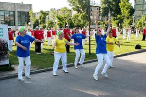 Dnepr, Ucrânia - 21.06.2021 uma grupo do idosos pessoas fazendo saúde e ginástica ginástica com uma bola dentro a parque. foto