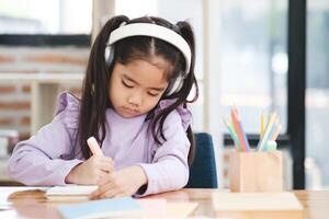 uma jovem menina é sentado às uma escrivaninha e escrevendo dentro uma caderno foto