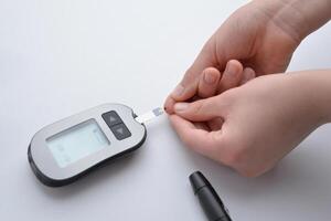 aplicando sangue a partir de dedo para faixa e dispositivo para medindo sangue glicose níveis. conceito do saúde monitoramento e diabetes gestão foto