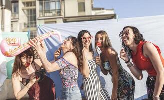 grupo do fêmea amigos tendo Diversão com festa acessórios em a telhados foto