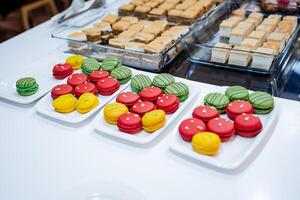 Macarrão do brilhante cor mentira em uma prato dentro uma restaurante, uma mesa com doces, manhã pastelaria dentro uma cafeteria, volta biscoitos dentro Esmalte, uma bufê distribuição. foto