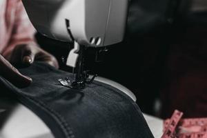 mulher costura roupas em uma máquina de costura nas mãos visíveis do quadro.