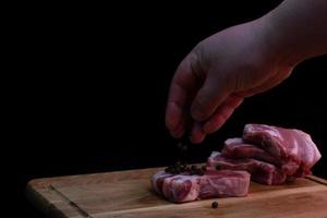 pedaço de peito de porco em uma placa de cozinha em um fundo escuro. foto