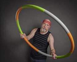 Senior homem é exercício com uma pesada hula aro foto