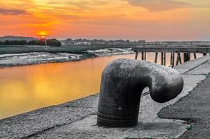 poste de amarração, grampo de ferro com pôr do sol colorido foto