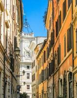 rua estreita de roma e igreja branca com sinos foto