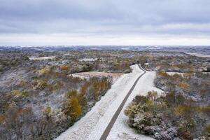 cascalho estrada, floresta e colhido milho campo Empoeirado de cedo neve, aéreo Visão do querida Riacho conservação área dentro ocidental Missouri foto