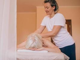 idosa caucasiana elegante mulher com cabelos grisalhos durante uma massagem. anti-idade, estilo de vida saudável, conceito de massagem foto